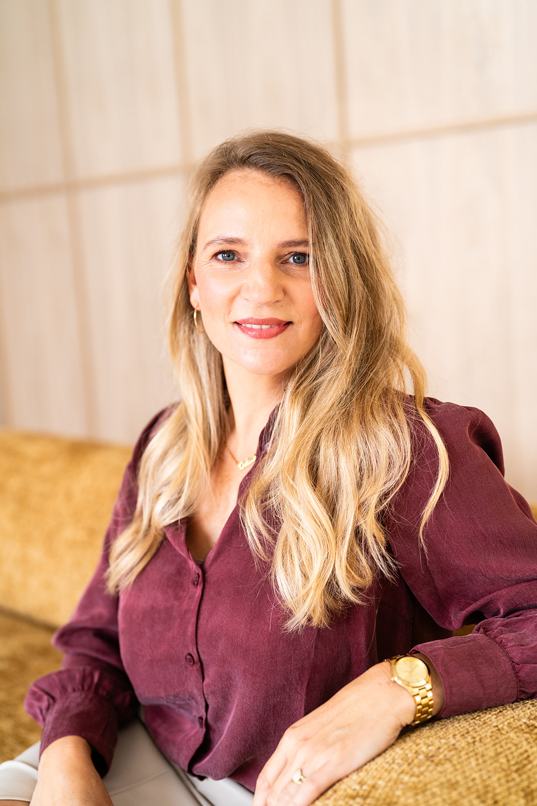 Marly in a burgundy blouse with gold jewelry, with a warmer look