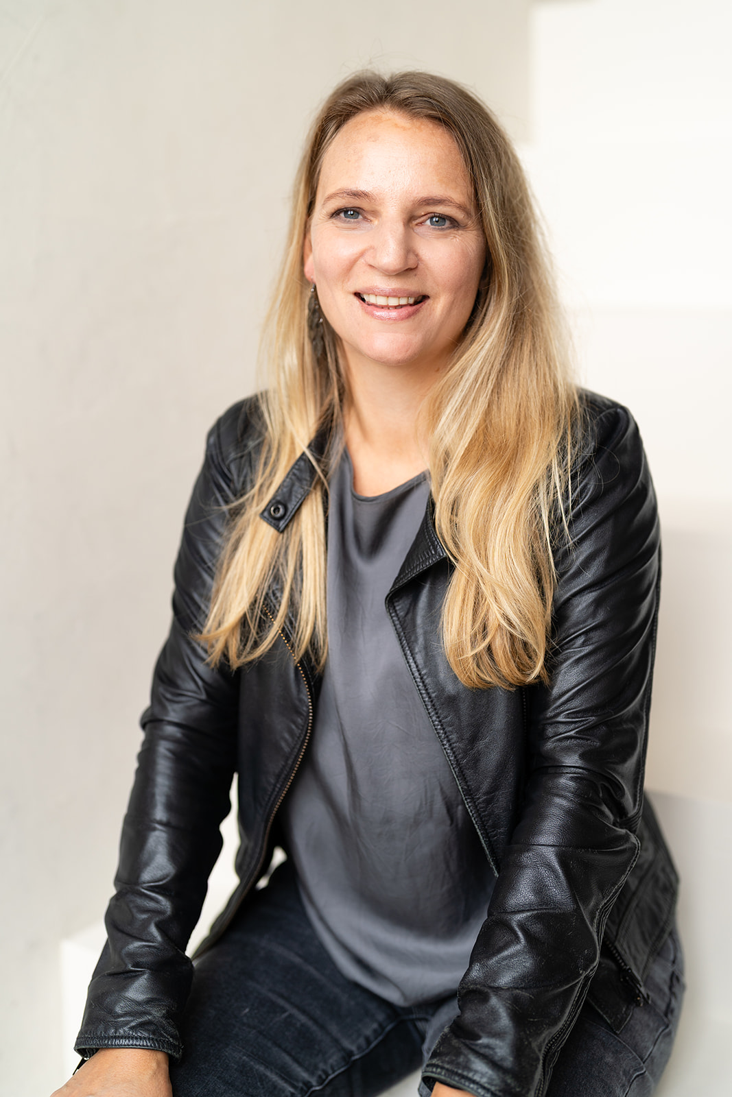 Marly in a black leather jacket with a grey shirt in cool, harsher colors