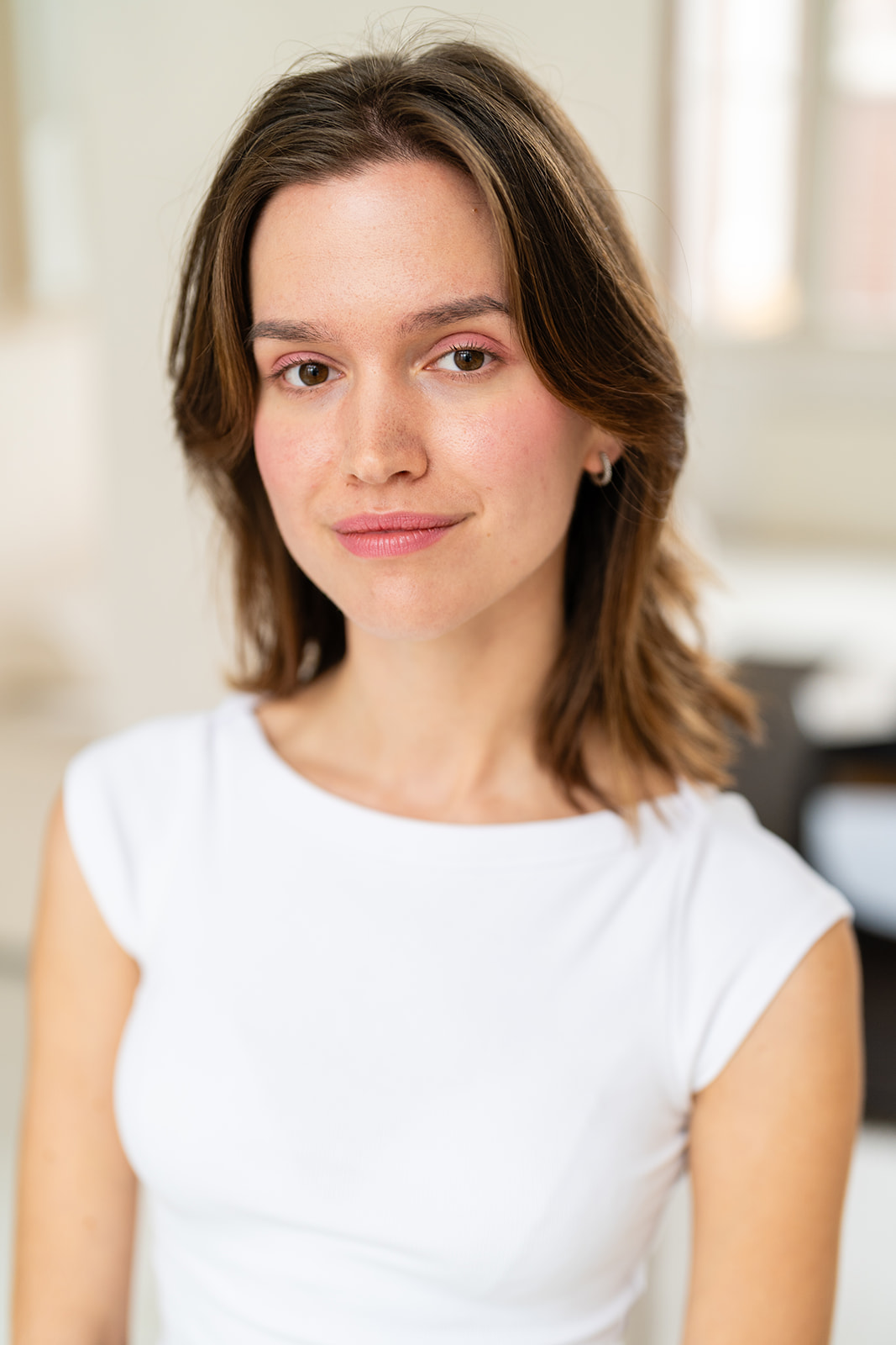 Brown-haired model in a white sleeveless shirt with cool pink make-up